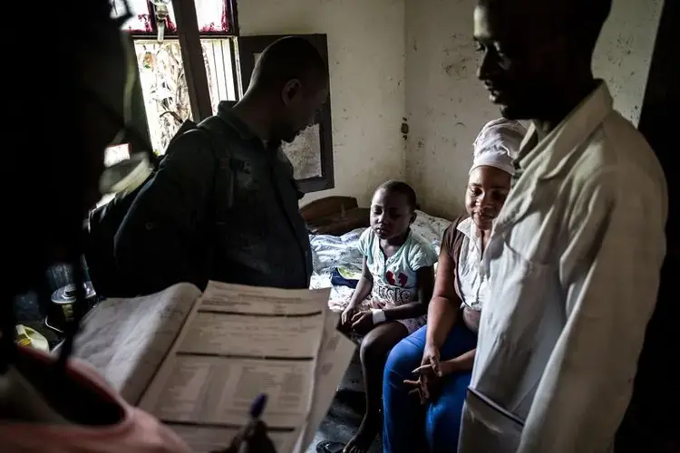 Health workers in Aloya try to convince a mother to send her child to an Ebola treatment centre. Image by John Wessels. Democratic Republic of Congo, 2019.<br />