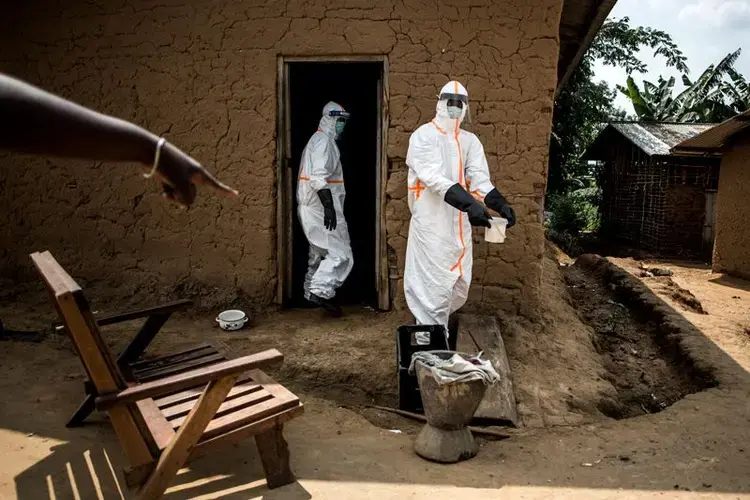 Ebola responders disinfect a home in Aloya in which three people have died. Image by John Wessels. Democratic Republic of Congo, 2019.<br />