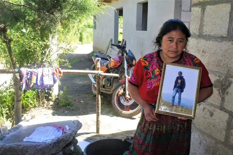 Lidia Carreto, 40, holds a framed photo of her 16-year-old son, Davin, who died trying to immigrate illegally to the United States in June 2018 near Laredo, Texas. Davin’s body was repatriated to San Juan, Ostuncalco, in a closed casket. Carreto concluded it was her son’s after recognizing his basketball shoes, sent in a clear plastic bag. Image by Kristian Hernandez. Guatemala, 2018.