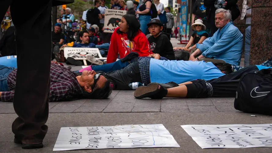Residents of Grassy Narrows and their supporters lie on the ground in front of the Indigenous Services Canada Office in Toronto. The community organized a 'die-in' in front of the office to remind the Canadian government of their suffering. Image by Shelby Gilson. Canada, 2019.