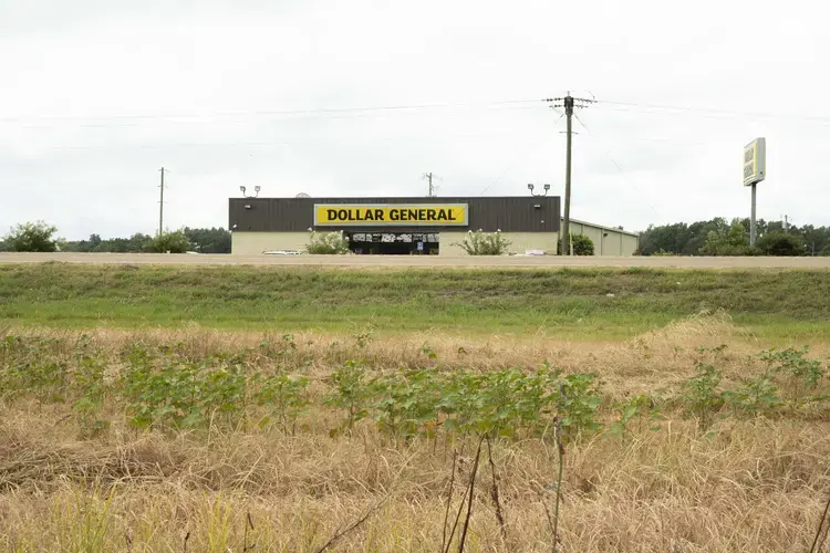 A Dollar Tree store sits directly across Highway MS-12 from a field of beans growing in Tchula, MS. Grocery stores are scarce in Holmes County, Mississippi, a place historically at the top of the list for poorest counties in the state. Discount variety stores often serve as the nearest source of food, mostly processed, despite the dominantly agricultural landscape. Image by Sarah Warnock/MCIR. United States, 2020.