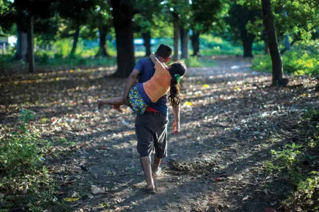 Not Leaving Family Behind | Arnovis carries his daughter, Meybelin, at their home on El Salvador’s coast. Image by Jose Cabezas. El Salvador, 2018.