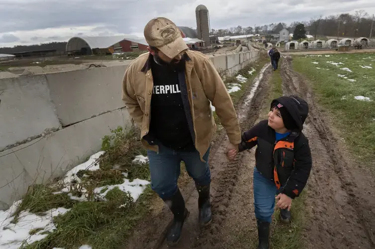 Tyler Gailloreto walks with his 6-year-old son, Leo, on their farm in Fort Atkinson. Image by Mark Hoffman. United States, 2019.