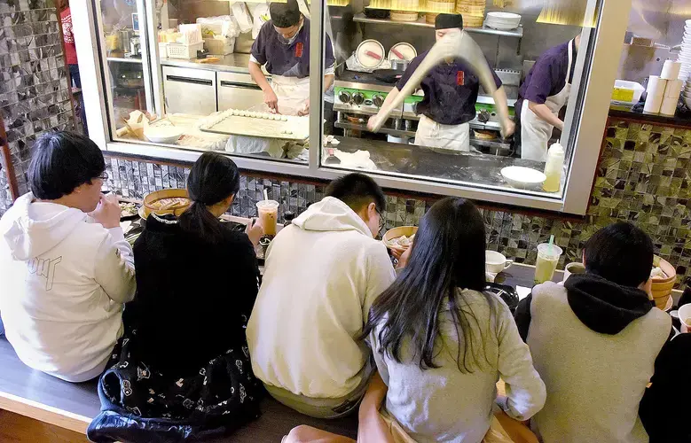 Jung Liu throws and stretches a long strand of dough in front of diners at Everyday Noodles in Squirrel Hill. Image by Darrell Sapp. United States, 2018.
