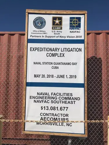 A sign outside the maximum-security Expeditionary Legal Complex, mistakenly labeled a litigation complex, illustrates ongoing construction that the public is prohibited to see at the U.S. Navy base at Guantánamo Bay, Cuba, on Nov. 8, 2018. A Pentagon official reviewed this photo and approved its release. Image by Carol Rosenberg. Cuba, 2018.