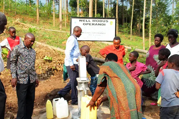 Residents of Kabende village in Kabarole District crowd at a water source to fetch water. Image by Felix Basiime. Uganda, undated.