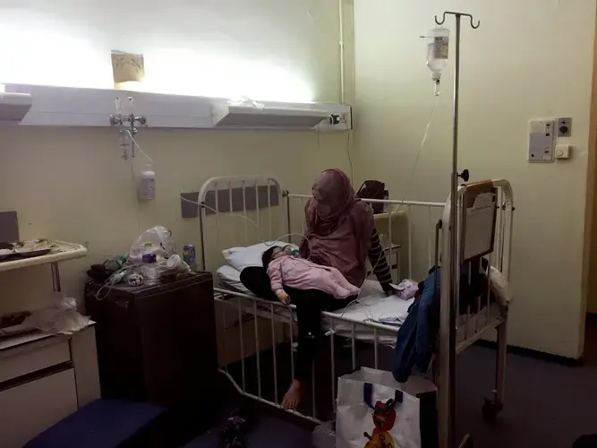 Taimaa Abazli with her sick baby Heln in a hospital in Thessaloniki, Greece. Baby Heln was diagnosed with an acute bronchial infection and doctors wanted to keep her on an IV drip for three days. Image by Lynsey Addario. Greece, 2017.