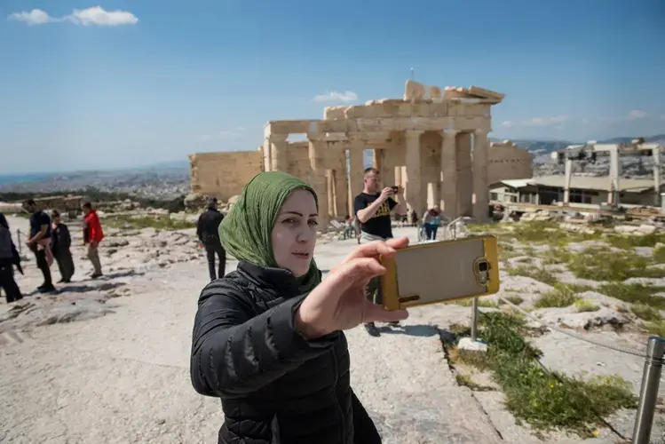 Syrian refugee, Taimaa, shoots a selfie while visiting the Acroplis in Athens. Image by Lynsey Addario. Greece, 2017.