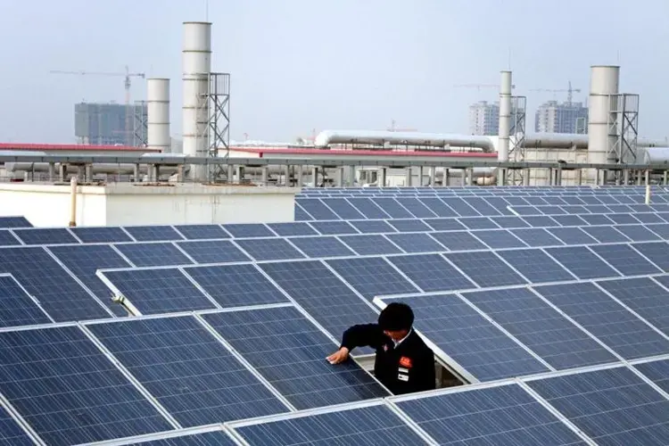 A worker cleans a solar panel on top of a factory building in Baoding City. China is installing a soccer field's worth of solar panels every hour. Image by Sean Gallagher. China, 2017.