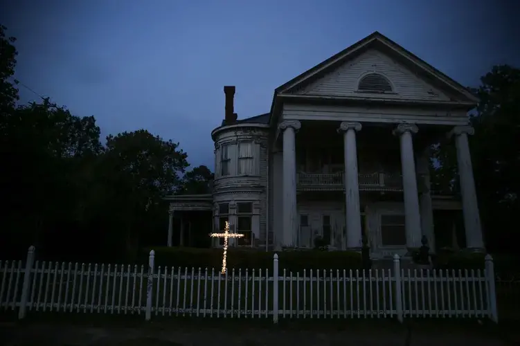 An illuminated cross stands in front of a residence near downtown Dawson, Ga., on Friday, April 17, 2020. Of the 20 counties with the highest death rate in America, six of them are in rural southwest Georgia, where there are no packed skyrise apartment buildings or subways. Image by Brynn Anderson / AP Photo. United States, 2020.