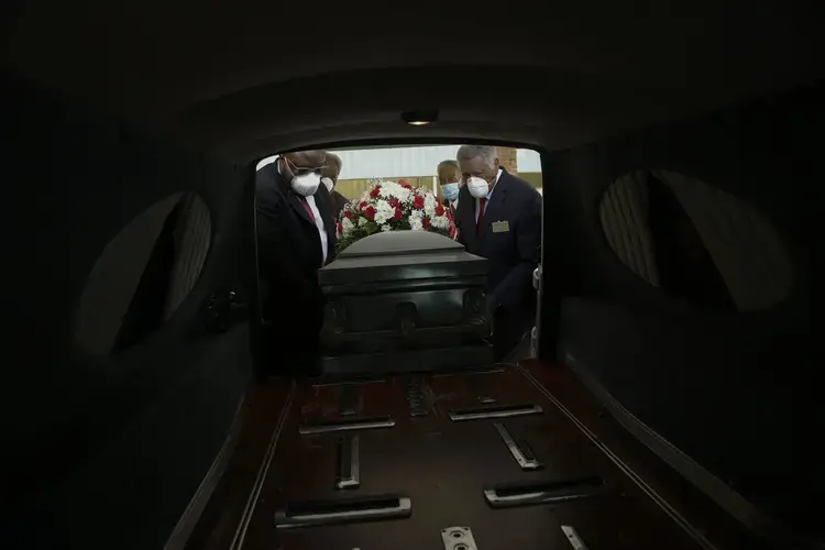 Mortician Cordarial O. Holloway, foreground left, funeral director Robert L. Albritten, foreground right, and funeral attendants Eddie Keith, background left, and Ronald Costello place a casket into a hearse on Saturday, April 18, 2020, in Dawson, Ga. Image by Brynn Anderson / AP Photo. United States, 2020.