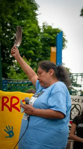 Gloria Fobister raises a feather over her head following her reading of a prayer that ended the march. Image by Shelby Gilson. Canada, 2019.