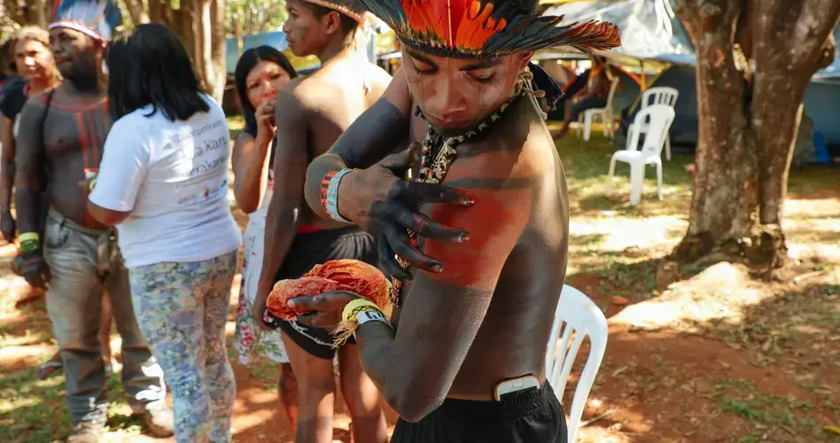 A member of the Guajajara tribe applies body paint in preparation for a protest. Image by Sam Eaton. Brazil, 2018.