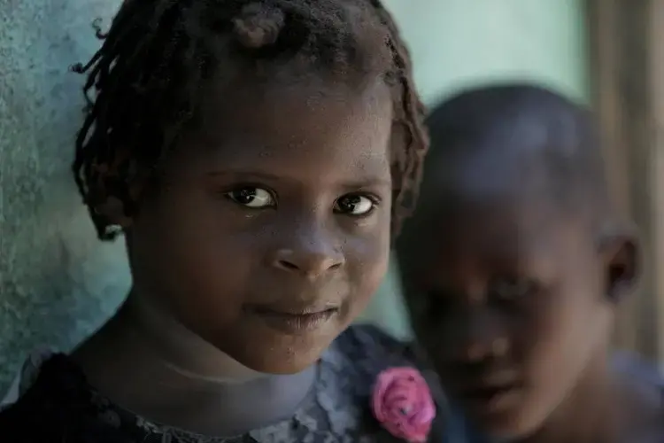 Marie Stacey (left), 6, and her friend Lukenson, 4, are curious about visitors to their town, Bellanger in Haiti’s Artibonite Valley. The girl’s mother, Paula Paul, has advanced cervical cancer. Image by José A. Iglesias. Haiti, 2018.