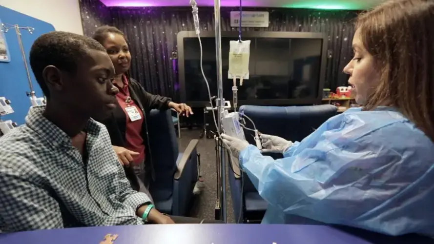 Baptist Health nurse Sahidy Aguilar tends to Djonsly Alcin, 14, as he receives chemotherapy. Baptist Health South Florida is taking care of Djonsly’s medical expenses while he’s here in the U.S. receiving treatment for a rare brain tumor. Image by José A. Iglesias. Haiti, 2018.