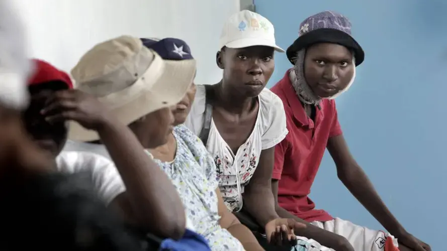 Djooly Jeune (right), 17, and his mother Angena Altidor wait with cancer patients at the University Hospital of Mirebalais. Djooly, who has Burkitt’s lymphoma, was unable to get his chemotherapy that day. Image by José A. Iglesias. Haiti, 2018.