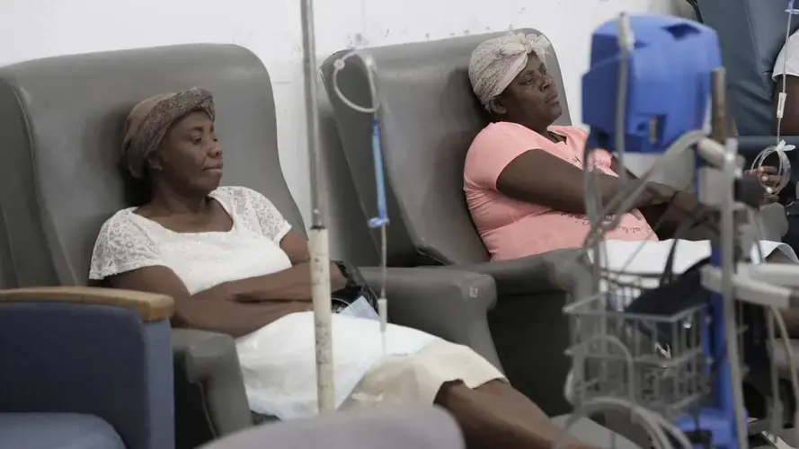 Paula Paul, right, and Feonia Licin patiently await the start of their chemotherapy at the University Hospital of Mirebalais in central Haiti. Paul has cervical cancer and Licin, breast cancer. Image by José A. Iglesias. Haiti, 2018.