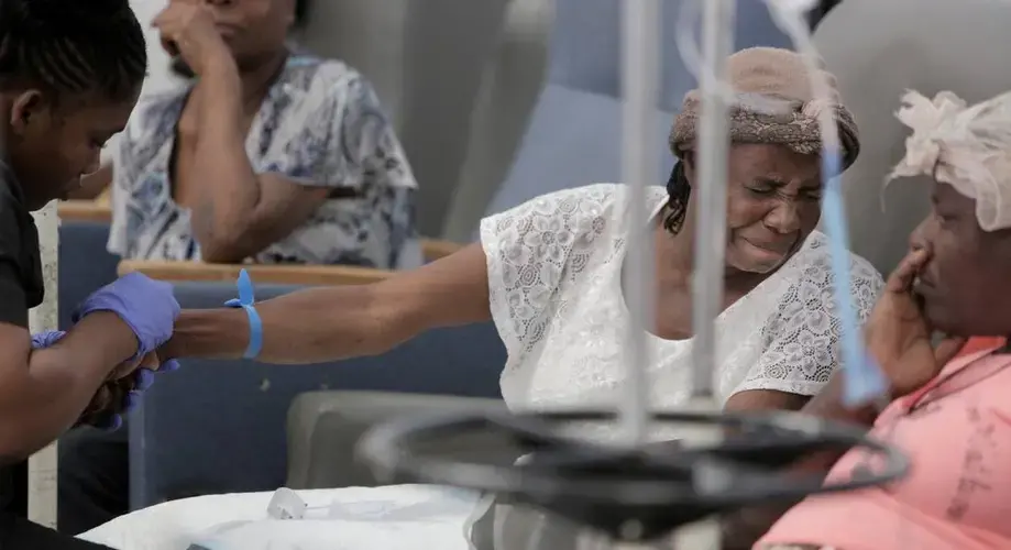 Feonia Licin, 51, grimaces as the nurse prepares her to receive chemotherapy. The mother of a 9 year-old son, Licin had a breast removed in December. Next to her is Paula Paul, 44, diagnosed in April with advanced cervical cancer. Image by José A. Iglesias. Haiti, 2018.