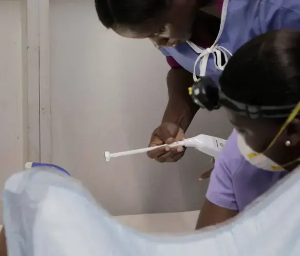A medical worker attaches a sterilized probe to a heat gun as midwife Nanotte Louis (right), prepares to treat a precancerous lesion. Image by José A. Iglesias. Haiti, 2018.
