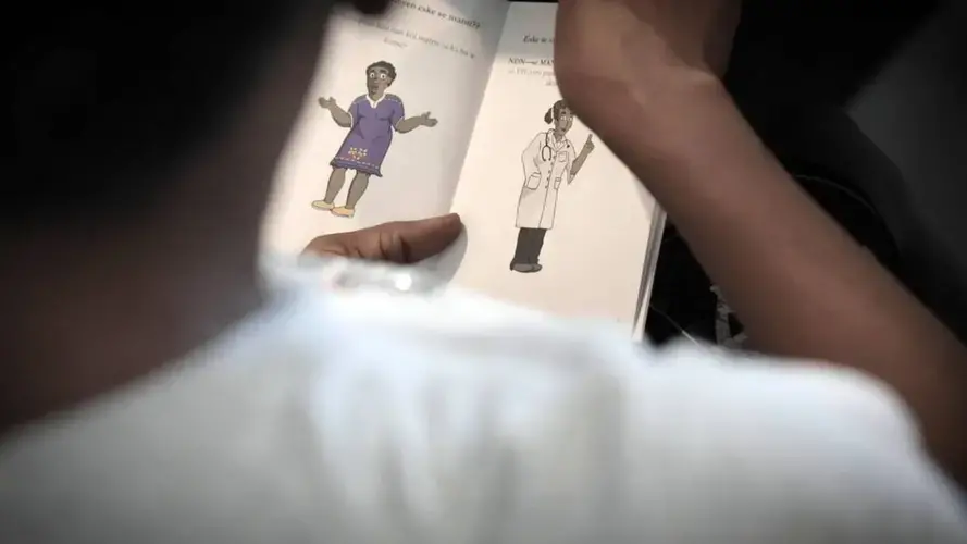 A female factory worker in Port-a-Prince, Haiti, looks through an information booklet on preventing cervical cancer while a midwife (not pictured) talks about using a self-sampler to test for HPV, the virus that’s the principal cause of the disease. Image by José A. Iglesias. United States, 2018.