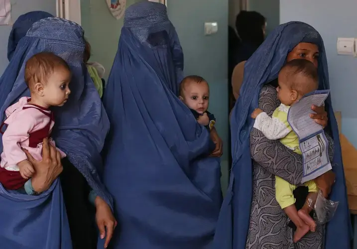 In this Aug. 26, 2019 photo, mothers hold their babies suffering from malnutrition as they wait at a UNICEF clinic in Jabal Saraj, north of Kabul, Afghanistan. Image by Rafiq Maqbool/AP Photo. Afghanistan, 2019.