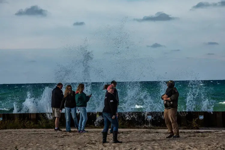 Visitors stand near crashing Lake Michigan waves at the Big Sable Point Lighthouse at Ludington State Park in Ludington, Michigan, on Sept. 30, 2020. A new seawall was put in place to protect the historic, still-active lighthouse. Image by Zbigniew Bzdak/Chicago Tribune. United States, 2020.