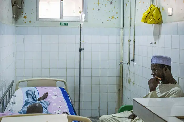 Ibrahim Adamu sits with his son Yusuf in an isolation room at Asokoro District Hospital in Abuja. Image by Misha Friedman. Nigeria, 2018. </p>
<p>
