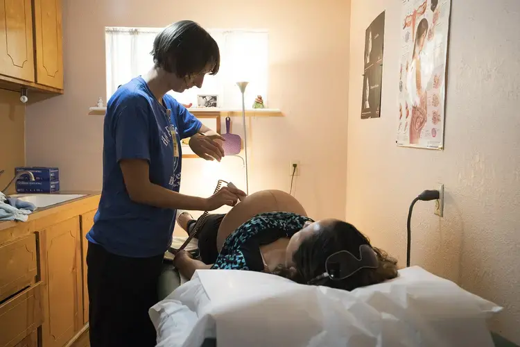 Vanna Waldron (left) evaluates Erika Piñon at the Holy Family Birthing Center in Weslaco, Texas. Waldron is a Certified Nurse Midwife from Seattle, Washington, who is volunteering at the birthing center for a year. Image by Reynaldo Leal for The Texas Tribune. United States, 2018.