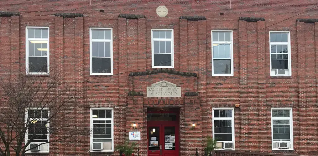 The front facade of the Sacred Heart Center. Behind the doors lie classrooms, a basketball court, space for worship, and, of course, Tanya Gonzales' office. Image by Jack Sims. United States, 2019.