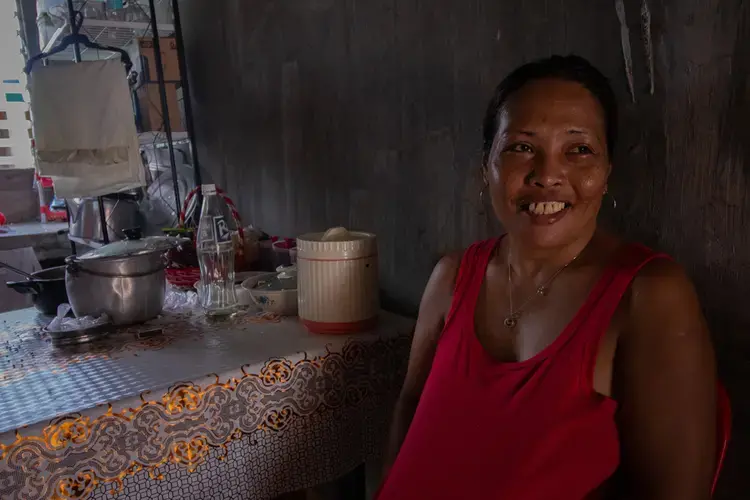 Divina Baniata, 43, inside her concrete unit at Summer Homes. She takes a break from doing laundry outside in 95-degree weather. Image by Micah Castelo. Philippines, 2019.