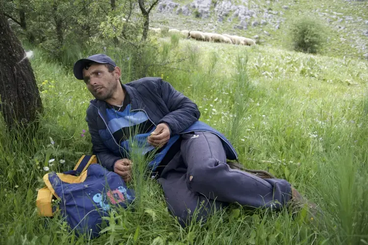 Jetmir Gjini hopes his son won't have to tend sheep like he does. He says the work keeps him away from his friends, family, everything. Image by Nate Tabak. Albania.