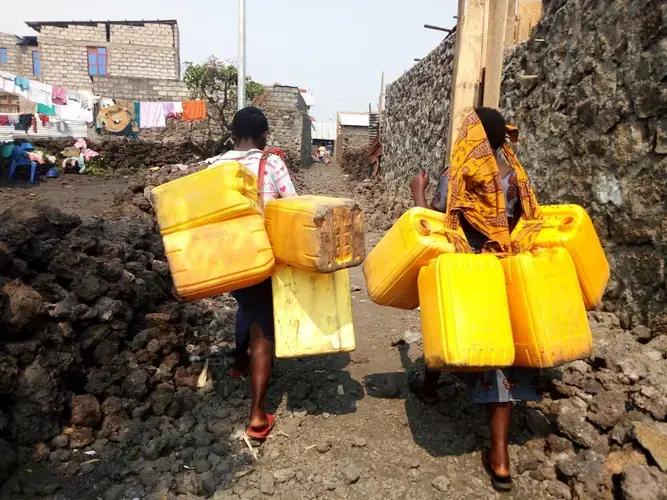 In a Goma neighborhood, such scenes have become part of the norm. They will usually be headed to neighborhood tap, or walking to Lake Kivu. Image by Fred Mwasa and Sylidio Sebuharara. Democratic Republic of the Congo, undated.