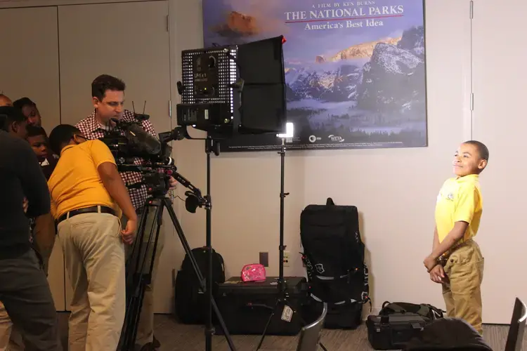Zach Fannin instructs on videography while a student beams in the spotlight. Image by Kim Pate. United States, 2018.