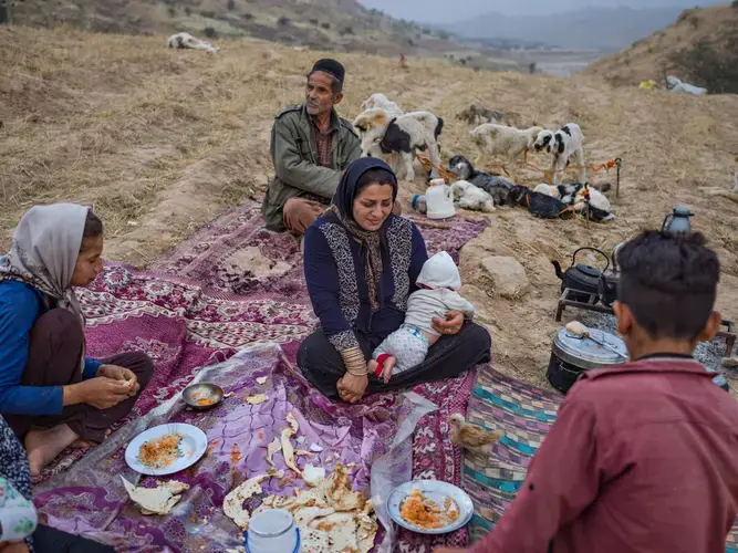 Stopping for the night, the Zamani family shares a meal laid out on colorful rugs. Image by Newsha Tavakolian. Iran, 2018.