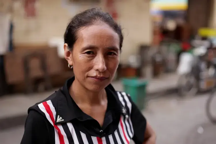Jiajia poses for a photo in the street outside her rented room in Huizhou, Guangdong province. Image by Max Duncan. China, 2016.