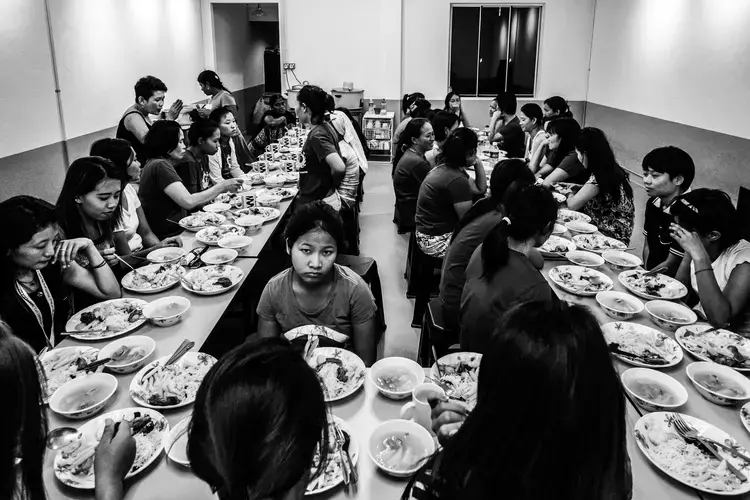 Runaway migrant workers shared a meal inside the kitchen of the shelter. Image by Xyza Bacani. Singapore, 2016.