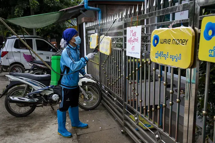 A volunteer sprays chemical disinfectant at a shop as a coronavirus prevention measure in Mrauk U on Aug. 21. The township, along with the rest of the state, was placed under a stay-at-home order on Aug. 26. Image by Hkun Lat/Foreign Policy. Myanmar, 2020.