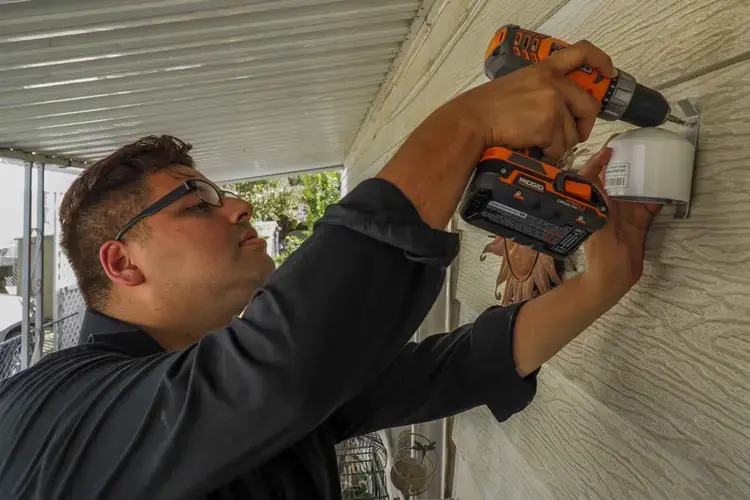 Yanni Gonzalez, a public outreach and community coordinator for the Central California Asthma Collaborative, installs an air quality monitor at the home of Kira Hinslea. Image by Larry C. Price. California, 2018.