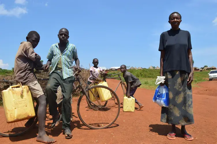 Lilian Omoro, a 20-year resident of Nakalanga village, poses with village children collecting water. Image by Annika McGinnis. Uganda, 2019.
