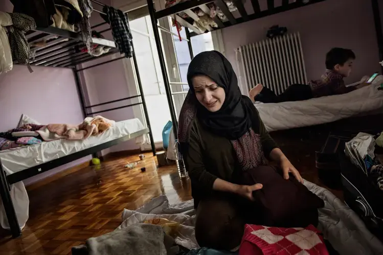 Syrian refugees Taimaa Abzali, her husband Muhanned Abzali, their six month old daughter, Heln, and son Wael, pack their memories and belongings the night before leaving for relocation in Estonia. Image by Lynsey Addario. Greece, 2017.