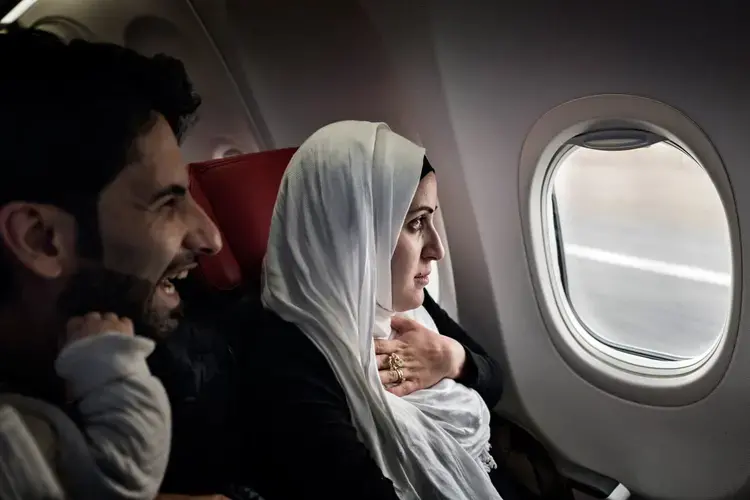Syrian refugees Taimaa Abzali and her husband Muhanned Abzali, look out the window with a mix of fear and excitement as they see Estonia from the air for the first time. Image by Lynsey Addario. Estonia, 2017.