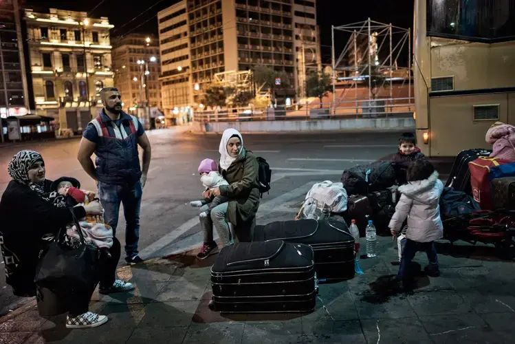 Syrian refugee Taimaa Abzali and her husband Muhanned Abzali, and their six month old daughter, Heln, and son Wael, wait in Athen's Ommonia square for transfer to the airport alongside Muhanned's brother Mufeed, his wife, Iman, and their two children, from Athens to Estonia for relocation. Image by Lynsey Addario. Greece, 2017.