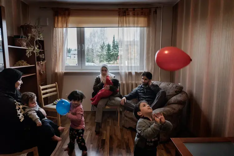 Syrian refugees Muhanned and Taima Abzali and their two children sit with Muhanned's brother's family of Mufeed and Iman Ateek and their two children in Mufeed and Iman's new apartment about one mile from Muhanned and Taimaa's in Polva, Estonia. Image by Lynsey Addario. Estonia, 2017. 