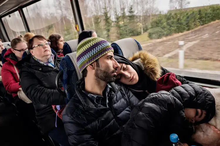 Syrian refugees Taimaa Abzali and her husband Muhanned Abzali, and their six month old daughter, Heln, and son Wael, take the bus in the early morning in the sleet and snow as they make their way to their orientation with IOM on their second full day in Estonia. Image by Lynsey Addario. Estonia, 2017. 
