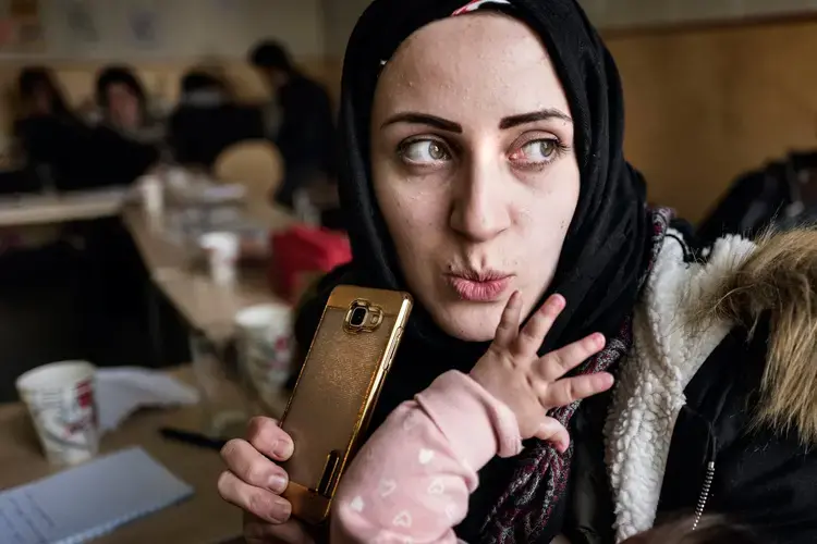 Syrian refugee Taimaa Abxali records Whats app messages in response to her loved ones who have called and messaged about how she and the family are doing, during a break at an orientation for new Syrian families given by IOM on their second full day in Estonia. Image by Lynsey Addario. Estonia, 2017.