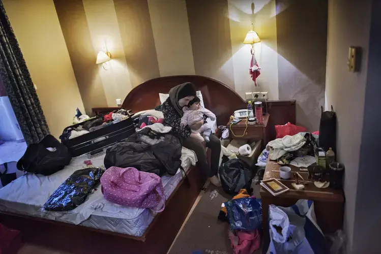 Syrian refugee Taimaa Abazli, 24, cuddles baby Heln, born Sept. 13, 2016, while packing the family's belonging in a hotel room in Giannitsa, Greece after hearing they will have an asylum interview the following morning in Athens.  Image by Lynsey Addario. Greece, 2017.