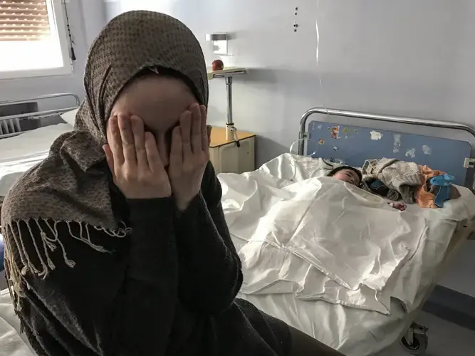 Syrian refugee Taimaa Abazli sits with her 4-month old daughter, Heln, in an Athens hospital. Image by Lynsey Addario. Greece, 2017.