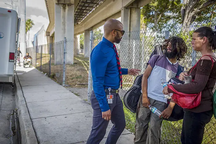 Physician Hansel Tookes (left), who oversees a needle exchange program in Miami's Overtown neighborhood, meets with Natasha Dixon (right) and Erik Olivero (center). Image by Misha Friedman. United States, 2018. 
