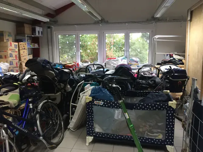 A storage room at the shuttered Sumte camp is packed with donations for the hundreds of families from Syria, Afghanistan, Iraq, and across Africa and the Middle East who had lived here. In September 2016, the refugees have left and the strollers are unused. Image by Valerie Schmidt. Germany, 2017.