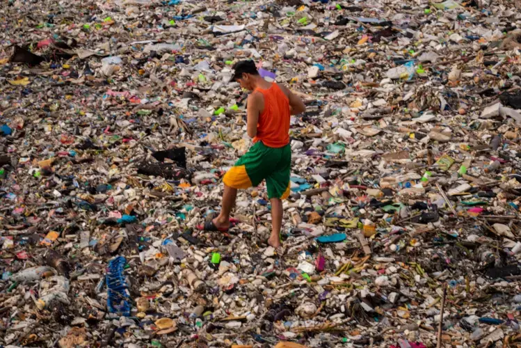 A man sifts through a sea of trash in Navotas, looking for “kalakal,” recyclable items and scraps he can sell to a junk shop. Image by Micah Castelo. Philippines, 2019.